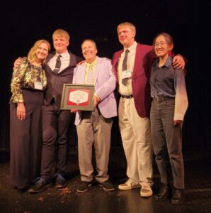 John Carney (center) poses on stage with an award next to his wife and three children